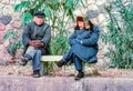 two old men in thick clothes in winter sitting on a bench in front of the wall of forbidden city in Beijing Royalty Free Stock Photo