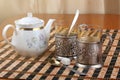 Two old metal cup holder with a bas-relief on the table with white porcelain teapot Royalty Free Stock Photo