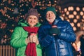 Two old people woman man have x-mas christmas jolly time night walk hold hot warm takeout beverage mug in city center Royalty Free Stock Photo