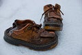 Two old ragged brown boots on the snow