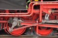 Two old red driving wheels of a steam locomotive engine with steam