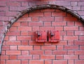 Two old red metal fire switches on an exterior brick wall