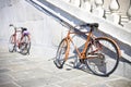 Two old rusty bicycles against a marble wall