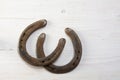 Two old rusty horseshoes on white painted wood, symbol for good Royalty Free Stock Photo