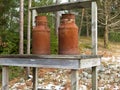 Two old rusty milk jug on a bench