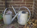 Two old rusty tin watering can in cemetery wall Royalty Free Stock Photo