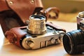 Two old school vintage photo cameras on light brown table. One in brown retro leather case holder Royalty Free Stock Photo