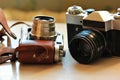 Two old school vintage photo cameras on light brown table. One in brown retro leather case holder Royalty Free Stock Photo