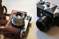 Two old school vintage photo cameras on light brown table. One in brown retro leather case holder Royalty Free Stock Photo