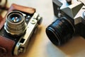 Two old school vintage photo cameras on light brown table. One in brown retro leather case holder Royalty Free Stock Photo