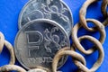 Two old scratched Russian ruble coins and a rusty chain on a blue background