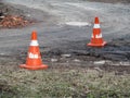 Two old shabby construction cones are on a dirt road. Orange Traffic cones with shabby white stripes against the background of Royalty Free Stock Photo