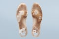 Two old, shabby orthopedic insoles isolated on blue background. Dirty leather insoles. Worn out things with holes. Inner