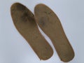 Two old, shabby orthopedic insoles isolated on white background. Dirty leather insoles.