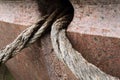 Two old textured ropes stick out of a hole in brown marble stone monument Royalty Free Stock Photo