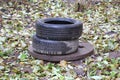 Two old used car tires are lying on the concrete manhole cover