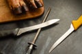 Two old and used the knife for meat boning and hand sharpener against a dark background.