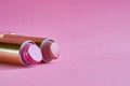 Two old used lipstick tubes lie on a pink background