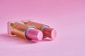 Two old used lipstick tubes lie on a pink background