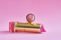 Two old used lipstick tubes on pink background