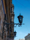 Two old vintage black dark glass street lanterns hanging on textured wall of beautiful building of Saint Petersburg. Blue sky Royalty Free Stock Photo