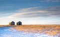 Two old vintage farm sheds on a winter field