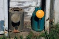 two old watering cans - metal steel grey watering can and plastic green and yellow watering can near the barn outside in Royalty Free Stock Photo