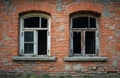 Two old weathered windows on a rustic brick wall. One window pane is intact. The other window has broken glass. Weathered Royalty Free Stock Photo