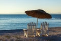 Two old beach chairs and sun umbrella on the background of the calm sea Royalty Free Stock Photo