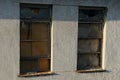 Two old windows with a broken stele boarded up with wooden plywood and metal on the brown concrete wall Royalty Free Stock Photo