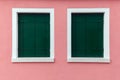 Two old windows with dark green shutters on light pink wall Royalty Free Stock Photo
