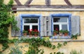 Two old windows with shutters and red geraniums Royalty Free Stock Photo