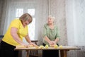 Two old women making little apple pies. Making a dough