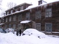 Two old women near a large wooden house talking in the winter