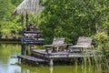 Two old wooden deck chairs near the lake water in a tropical garden, asia, Thailand Royalty Free Stock Photo