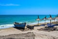 Two old wooden row-boats of different sizes on the sandy beach of the Black Sea, next to straw beach umbrellas on a clear, blue Royalty Free Stock Photo