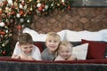 Two older brothers and little sister in bedroom. Three siblings have a fun on bed on Christmas decorations background. New year Royalty Free Stock Photo