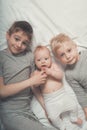 Two older brothers are lying with the youngest baby in a white bed. Happy childhood, big family Royalty Free Stock Photo