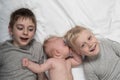 Two older brothers play and laugh with the youngest baby in a white bed. Happy childhood, big family Royalty Free Stock Photo