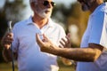 Two older men stand on a golf course and talk. Royalty Free Stock Photo
