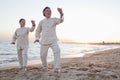 Two older people practicing Taijiquan on the beach at sunset, China Royalty Free Stock Photo