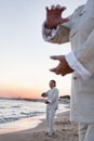 Two older people practicing Taijiquan on the beach at sunset, close up on hands Royalty Free Stock Photo