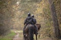 Two older people riding horses in the autumn forest Royalty Free Stock Photo