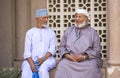 Two omani men in traditional clothing chatting at a old street m