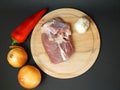 Two onions, pepper and pork fillet on a cutting board on a black background Royalty Free Stock Photo