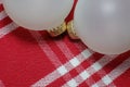 Two opaque white holiday christmas ornaments on a red and white Royalty Free Stock Photo