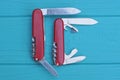 two open folding knives multitools with red handles with gray blades