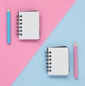 Two open notebooks with colored pencils, on a pink and blue diagonal background.