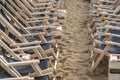Two opposing rows of suspended empty deck chairs in rows lined up in order on the beach in the sand Royalty Free Stock Photo