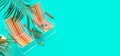 Two orange beach chairs with summer accessories on turquoise blue background